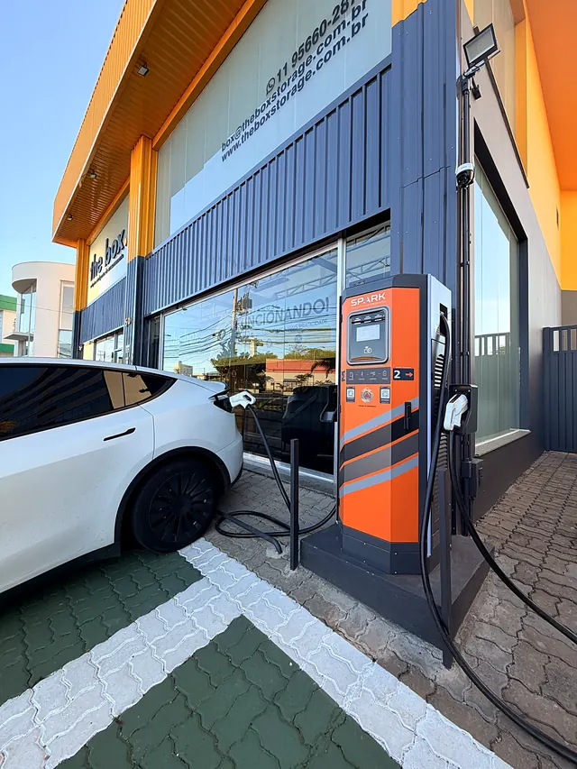 Carregador rápido Spark de 80 kW com um Tesla branco plugado na unidade de Itu